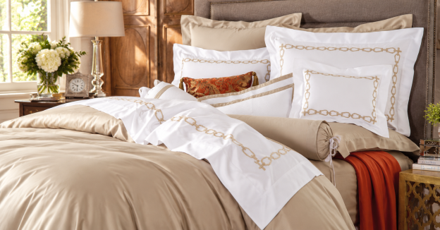 Elegant bedroom featuring Schweitzer Linen bedding with embroidered chain-link details, soft neutral tones, and warm natural light.