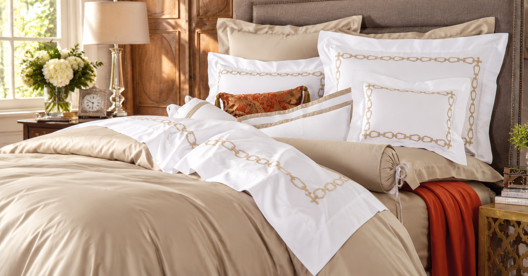 Elegant bedroom featuring Schweitzer Linen bedding with embroidered chain-link details, soft neutral tones, and warm natural light.